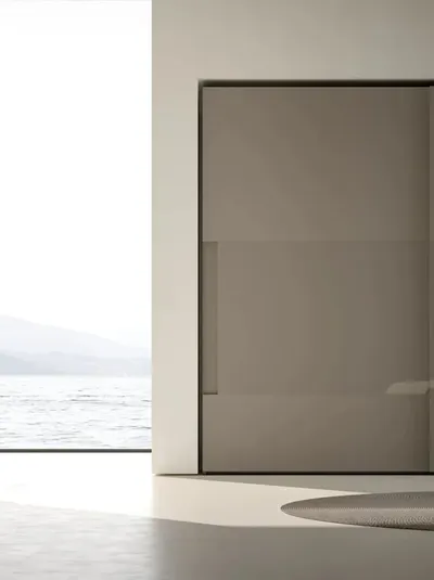 Armadio Atelier con ante scorrevoli con maniglia integrata in melaminico Fango e inserti in vetro Shine di Adok